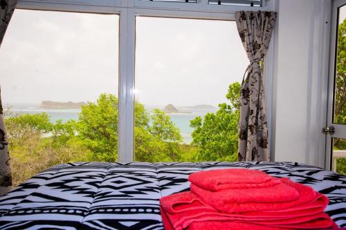 a bed with red towels on it in front of a window at GARNET--A gem at DEE'S PEARL in Carriacou
