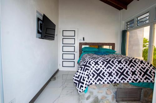 a bedroom with a bed and a tv on a wall at GARNET--A gem at DEE'S PEARL in Carriacou