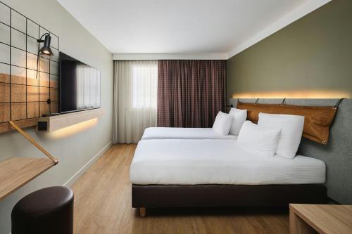 a hotel room with two beds and a television at Moxy Annecy in Annecy