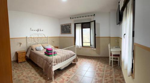 a bedroom with a bed and a table and a window at Casa Rural Al-Mofrag y Apartamentos El Mirador de Monfragüe in Villarreal de San Carlos