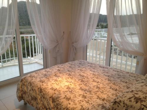a bedroom with a bed and a balcony with windows at Villa Carolina The Royal Links Sarigerme, Ortaca in Sarigerme