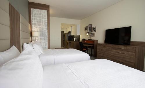a hotel room with two beds and a flat screen tv at Fiesta Inn Suites Aeropuerto del Bajío in Silao