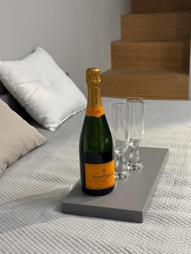 a bottle of wine and two glasses on a bed at SKY LUXURY Rooms Nettuno in Nettuno