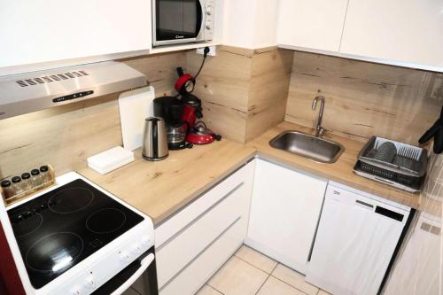 une petite cuisine avec une cuisinière et un micro-ondes dans l'établissement Résidence L'horizon - Belle exposition sud pour un appartement au calme. MAE-3924, à Le Mélézet