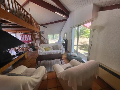 un salon avec des meubles blancs et une grande fenêtre dans l'établissement Villa Amapola, familiale et calme, à Lacanau