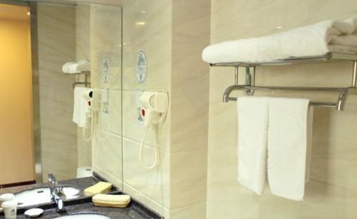 a bathroom with a sink and a mirror and towels at GreenTree Inn Beijing Shunyi Xinguozhan Express Hotel in Shunyi