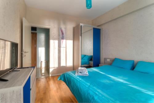 a bedroom with a blue bed and a television at Sea View Apartments MonteBook in Becici