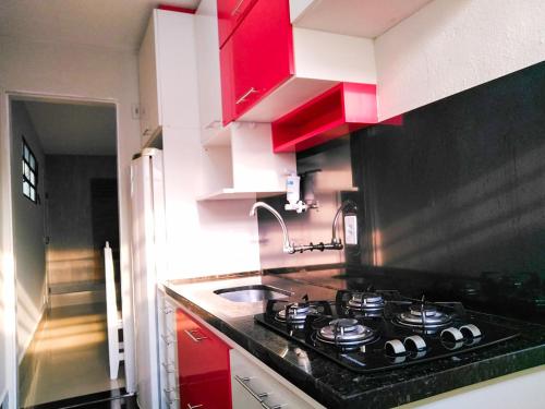 eine Küche mit Herd und roten Schränken in der Unterkunft Bate & Volta - Apartamentos com 2 quartos próximo ao SESC Bertioga in Bertioga