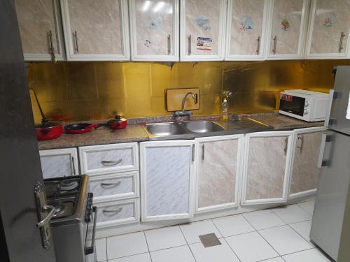 una cucina con mobili bianchi, un lavello e un microonde di Yasliving EXTN a Abu Dhabi