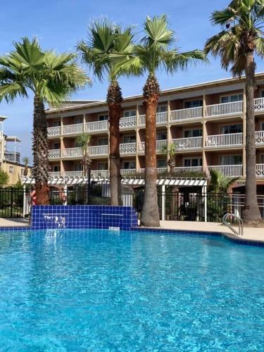 a large swimming pool with palm trees in front of a hotel at Ocean Front Condo - 3 Bdrms - Hot Tubs - 2 Pools - Gym - Tennis ct - SS2203 in Galveston