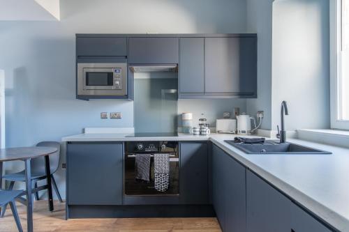 a kitchen with black cabinets and a sink and a stove at Prime Stay Apartments in Paisley