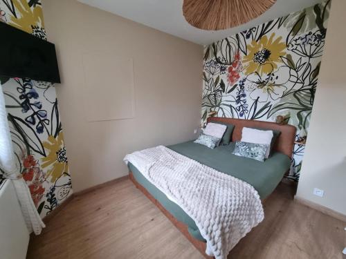 a small bedroom with a bed with a flowery wall at Le Petit Marais in Saint-Martin-lez-Tatinghem