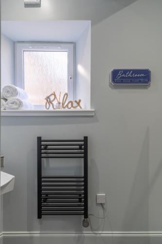 a bathroom with a mirror and a window and a shelf at Prime Stay Apartments in Paisley