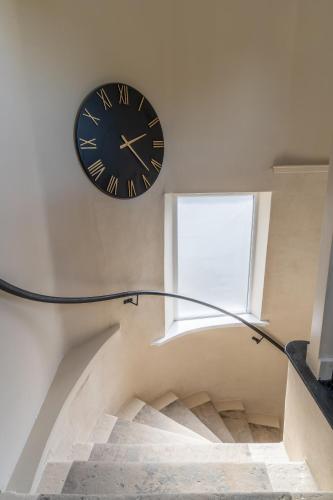 a clock hanging on a wall above a staircase at Prime Stay Apartments in Paisley