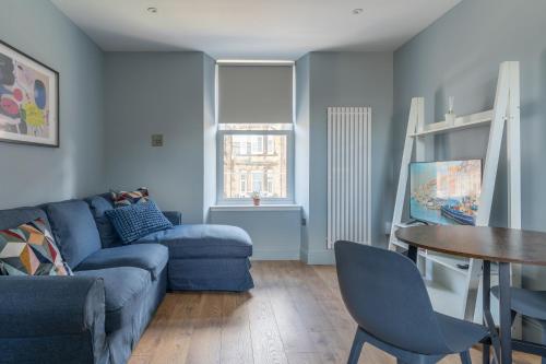 a living room with a blue couch and a table at Prime Stay Apartments in Paisley
