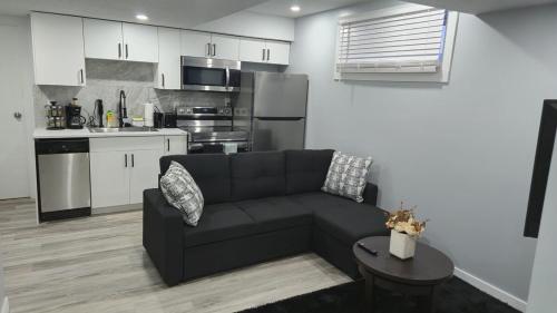 a living room with a black couch and a kitchen at Mercy's lodge in Saskatoon