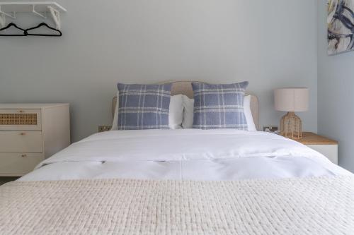 a bedroom with a white bed with blue pillows at Prime Stay Apartments in Paisley