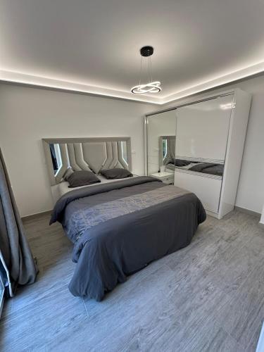 une chambre avec un grand lit et un grand miroir dans l'établissement Villa normande, à Villeneuve-le-Roi