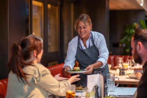a woman holding a plate of food in a restaurant at Burleigh Court Hotel and Leisure in Loughborough