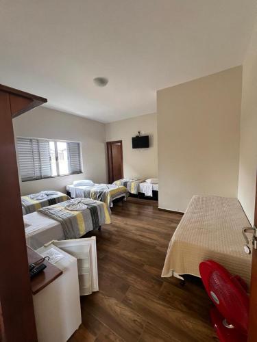 a room with four beds and a flat screen tv at Pousada Portal da Lua in São Thomé das Letras