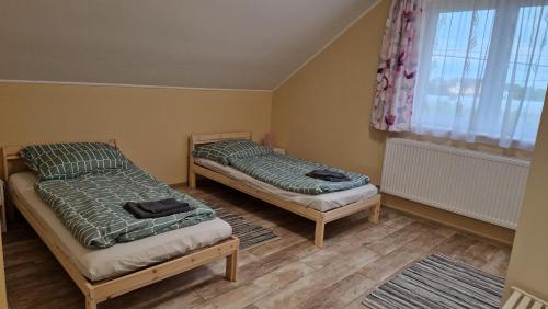 zwei Einzelbetten in einem Zimmer mit Fenster in der Unterkunft Levendula Vendégház in Nyírmeggyes