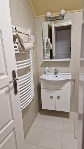 ein weißes Badezimmer mit Waschbecken und Spiegel in der Unterkunft Levendula Vendégház in Nyírmeggyes