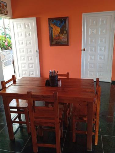 a wooden dining room table with chairs and orange walls at Casa campestre con piscina natural in Chipaque