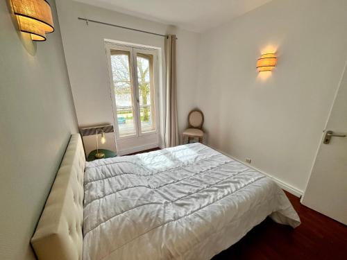 une chambre avec un lit blanc et une fenêtre dans l'établissement Hypercentre, douillet, vue Loire et vieux Blois, le Sérénity, à Blois