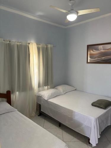 a bedroom with two beds and a window at Casa Branca in Saquarema