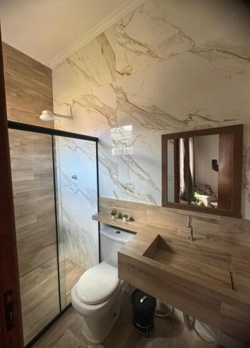 a bathroom with a toilet and a sink and a mirror at Serra Mar à beira rio , rafting, suites, lofts, e Casas in Sana
