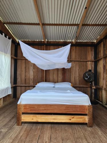a bed in a wooden room with a mosquito net at PRIMITIVO LODGE & dive center in Bahía Solano