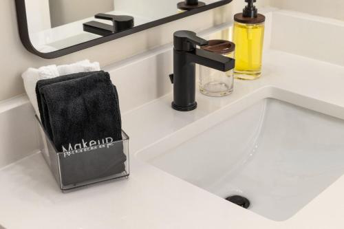 a white bathroom sink with a black faucet at 3BD Retreat - Hot Tub & BBQ - Near NCSU & Downtown in Raleigh