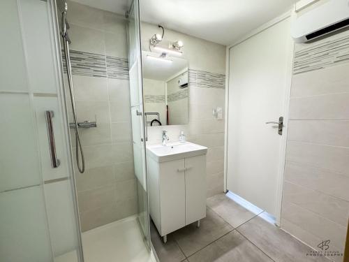 a white bathroom with a shower and a sink at Le Repaire de Leucate - Confort près de la Plage in Leucate-Plage