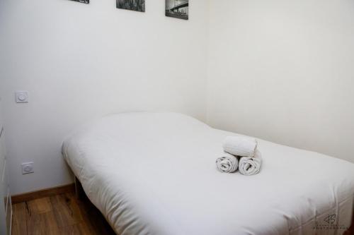 a white bed with two rolled towels on it at Le Repaire de Leucate - Confort près de la Plage in Leucate-Plage