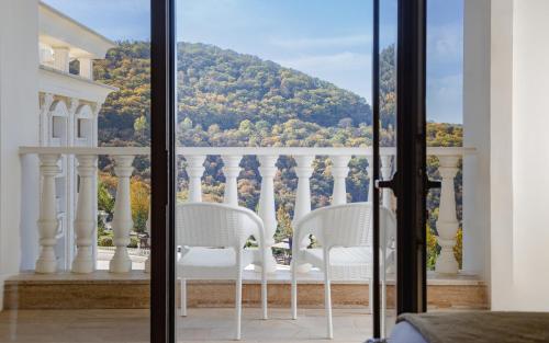 two white chairs sitting on a balcony with a view at Shamakhi Palace Sharadil in Şǝrǝdil