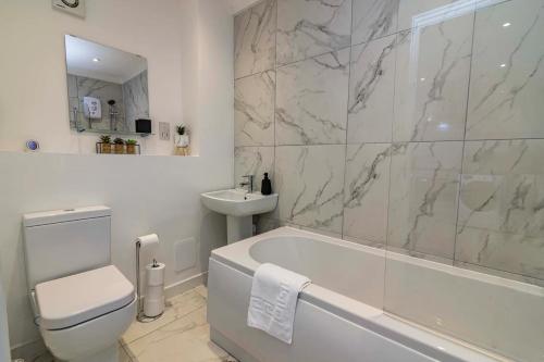 a bathroom with a tub and a toilet and a sink at 4br-sleeps8-privategarden-freeparking in Nottingham