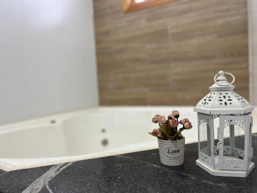 a vase of flowers and a lantern next to a bath tub at Espaço Amplitude in Sobradinho