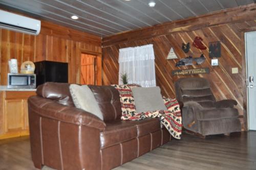 a living room with a leather couch and a chair at Restful River Cabin, Red River Gorge, KY, River Access & Views in Stanton