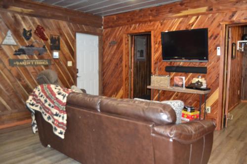 a living room with a leather couch and a flat screen tv at Restful River Cabin, Red River Gorge, KY, River Access & Views in Stanton