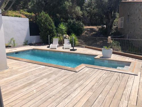 - une piscine avec 2 chaises sur une terrasse en bois dans l'établissement Bella vista, à Lumio