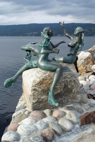a statue of two women sitting on a rock near the water at Villa Thorse in Husvik
