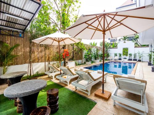 a patio with a pool and chairs and umbrellas at Rithy Rine Angkor Residence in Siem Reap