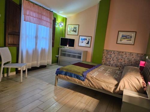 a bedroom with green walls and a bed and a television at Sa Mirada Apartments in Villasimius