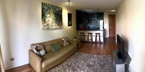 a living room with a couch and a kitchen at Mirando a Parque Arauco in Santiago