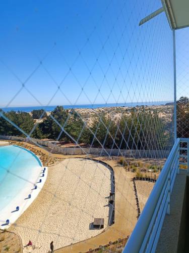 una vista de una piscina detrás de una red de voleibol en Depto Condominio Laguna Mar, en Las Cruces