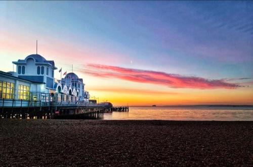 a pier on the beach with the sunset in the background at The Snug King Bed in Portsmouth