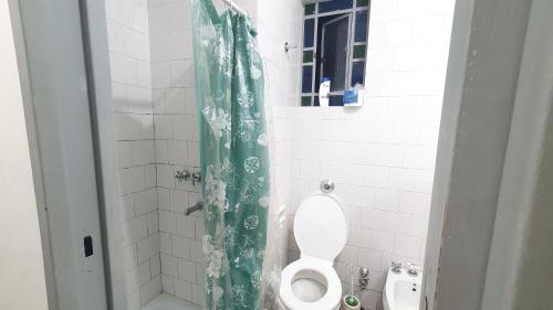 a bathroom with a toilet and a green shower curtain at Hostal 2 in Buenos Aires