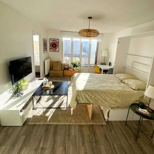 une chambre avec un lit, une table et une télévision dans l'établissement Bright studio near Paris & La Defense, à Asnières-sur-Seine