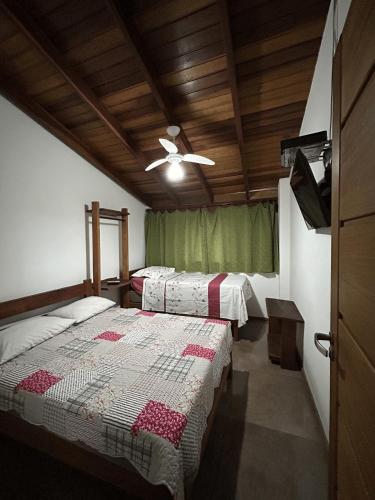 ein Schlafzimmer mit zwei Betten und einem Deckenventilator in der Unterkunft Vilarejo Leme in São Sebastião