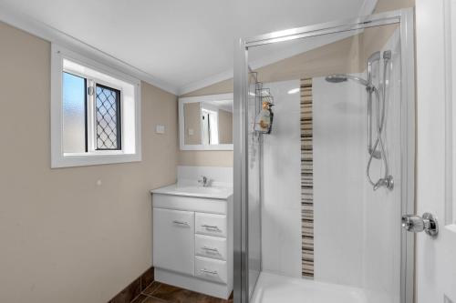 ein weißes Badezimmer mit Dusche und Waschbecken in der Unterkunft Quaint 2 bedroom fully furnished Cottage in Warwick